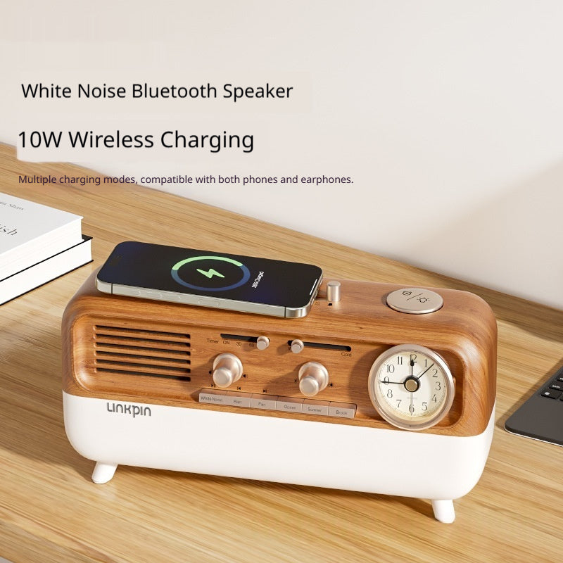 Retro Bluetooth speaker on a wood desk wirelessly charging a smartphone, books and laptop in the background