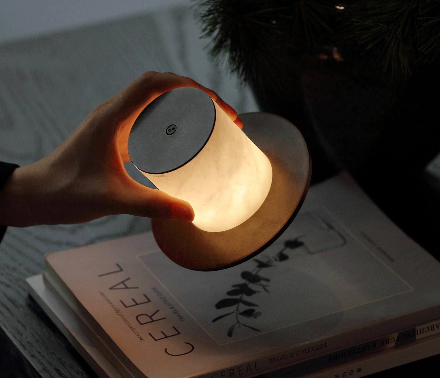 Hand holding the glowing cordless alabaster lamp over a magazine