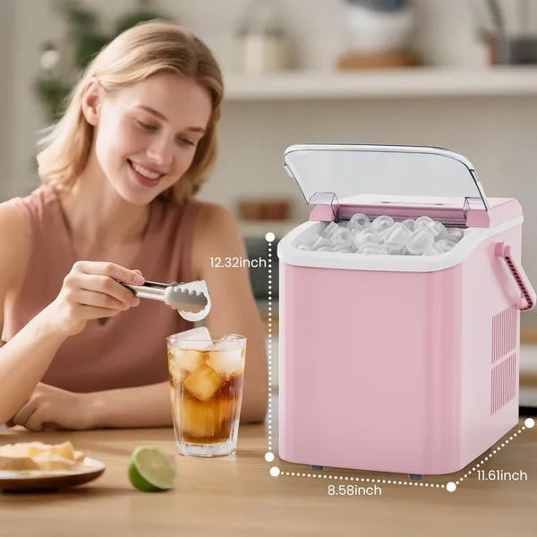Woman in a kitchen using tongs to drop bullet ice cubes into a tall glass of iced tea, the pink countertop ice maker beside her with the lid open and a lime on the table.