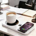 Smart Mug Warmer with Wireless Charging on a desk — a ceramic mug with latte art sits on the heating coaster side at 75°C while a smartphone charges wirelessly on the Qi pad side, with a desk lamp, notebook and papers in the background